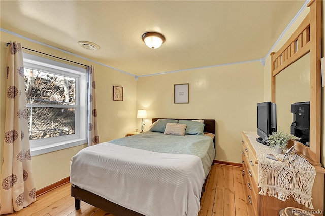 bedroom with light wood-type flooring, crown molding, and baseboards