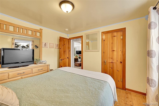 bedroom featuring light wood finished floors, baseboards, and ornamental molding