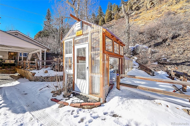 snow covered structure with an outbuilding and an exterior structure