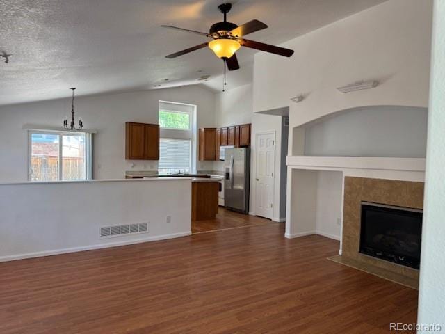 20148 E Dartmouth Dr, Aurora, CO 80013 - kitchen with stainless steel fridge, open floor plan, vaulted ceiling, dark wood-style flooring, and brown cabinets