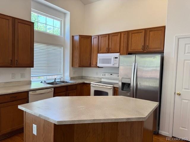 20148 E Dartmouth Dr, Aurora, CO 80013 - kitchen featuring white appliances, brown cabinetry, a sink, light countertops, and a center island