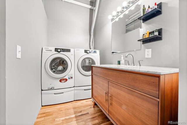 laundry room with light wood-type flooring, cabinets, sink, and washer and dryer