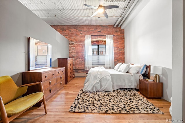 bedroom featuring light wood-type flooring, brick wall, and ceiling fan