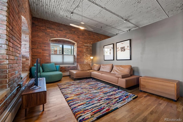 living room featuring hardwood / wood-style floors and brick wall