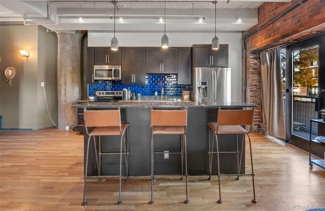 kitchen with stainless steel appliances, dark stone counters, light hardwood / wood-style flooring, and a center island