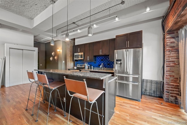 kitchen featuring appliances with stainless steel finishes, light hardwood / wood-style floors, a center island, and a breakfast bar area