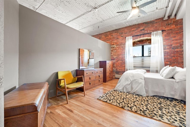 bedroom with hardwood / wood-style floors, brick wall, and ceiling fan