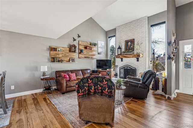 living area with lofted ceiling, wood-type flooring, a fireplace, and baseboards