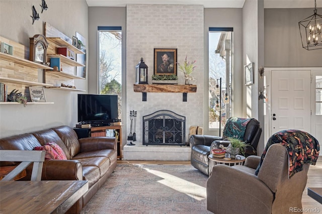 living area with wood finished floors, a fireplace, and an inviting chandelier