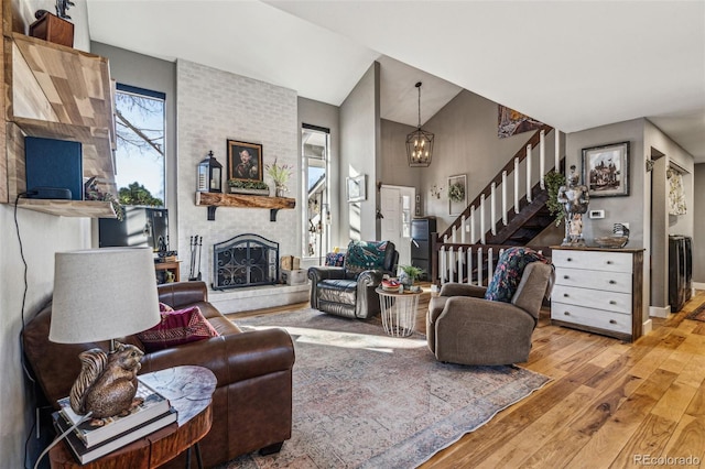 living area with baseboards, hardwood / wood-style flooring, stairway, vaulted ceiling, and a fireplace