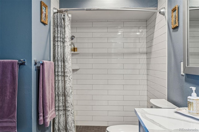 bathroom with tiled shower, a textured wall, vanity, and toilet