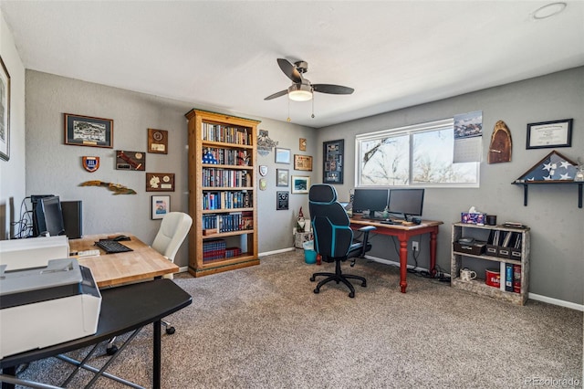 carpeted home office with ceiling fan and baseboards