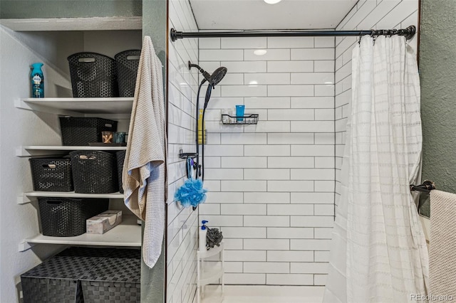 bathroom with a textured wall and a tile shower