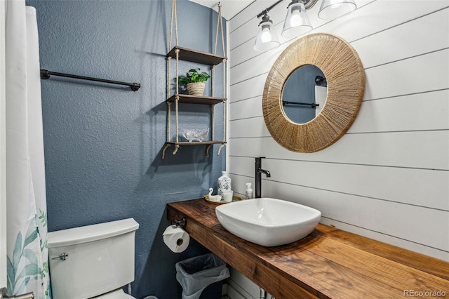 bathroom featuring a textured wall, a sink, and toilet