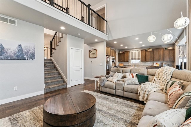 living room featuring baseboards, dark wood finished floors, visible vents, and stairway