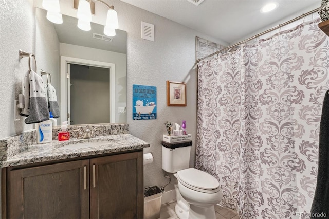 full bathroom with toilet, vanity, a textured wall, and visible vents