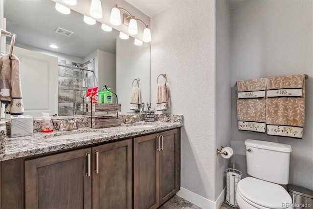 full bath featuring baseboards, a sink, toilet, visible vents, and a tile shower