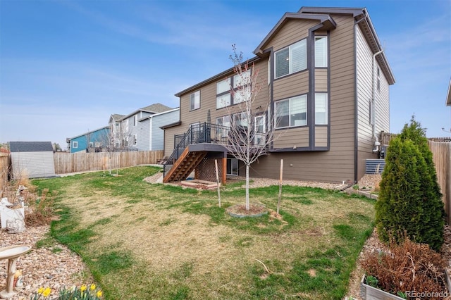 back of house with stairs, a fenced backyard, a storage shed, an outbuilding, and a deck