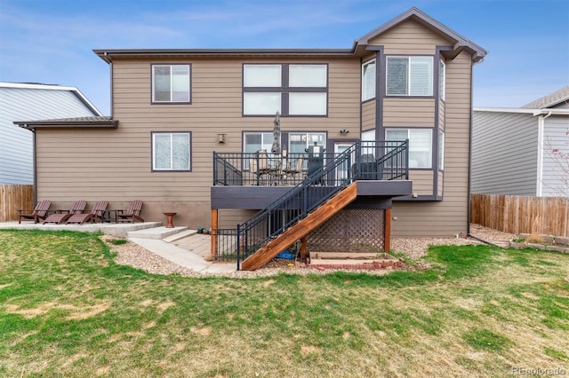 rear view of house with a yard, fence, a wooden deck, and stairway