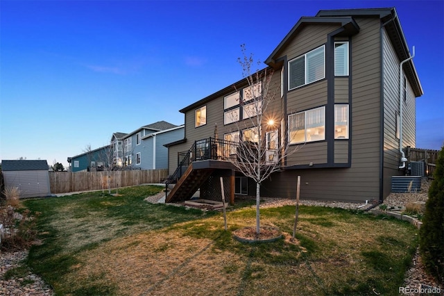 back of property featuring fence, an outdoor structure, a storage unit, and stairs