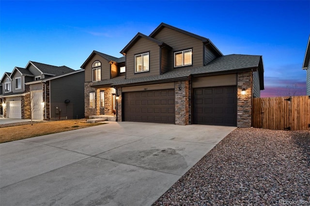 view of front of property with concrete driveway, stone siding, an attached garage, fence, and a shingled roof