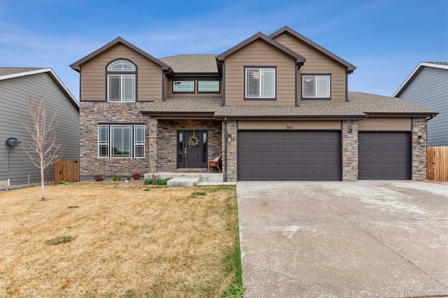 view of front facade with a shingled roof, stone siding, fence, concrete driveway, and a front lawn