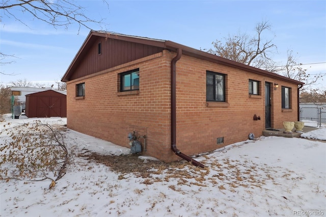 view of snowy exterior featuring a storage shed