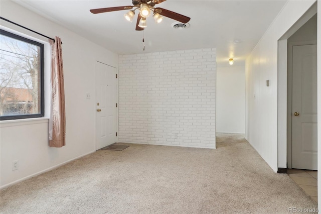 spare room with light carpet, ceiling fan, and brick wall