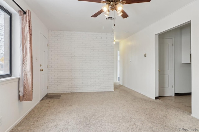 spare room featuring light colored carpet and brick wall