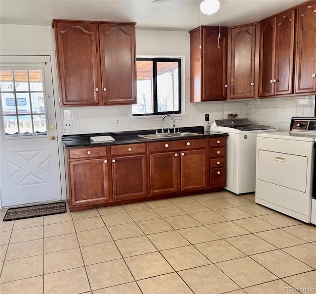 kitchen featuring light tile patterned flooring, independent washer and dryer, sink, and decorative backsplash