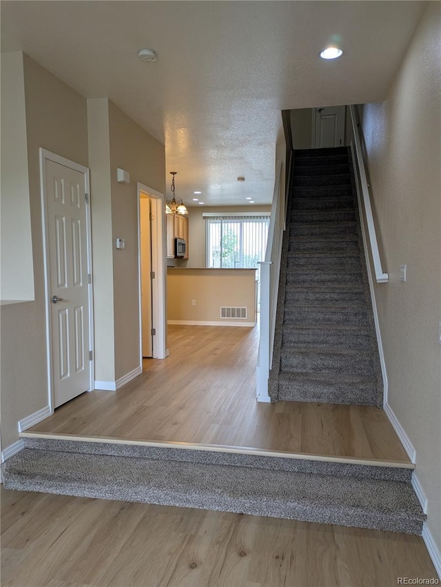 9578 Pearl Cir Unit 105, Parker, CO 80134 - staircase featuring wood finished floors, baseboards, and a chandelier