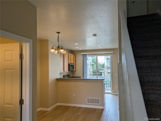 9578 Pearl Cir Unit 105, Parker, CO 80134 - kitchen featuring light wood-style flooring, stainless steel microwave, a textured ceiling, a chandelier, and baseboards