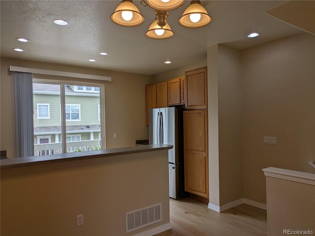 9578 Pearl Cir Unit 105, Parker, CO 80134 - kitchen featuring freestanding refrigerator, light wood-type flooring, recessed lighting, baseboards, and brown cabinets