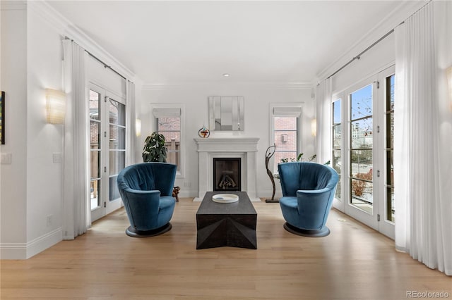 sitting room with crown molding, light hardwood / wood-style floors, and french doors