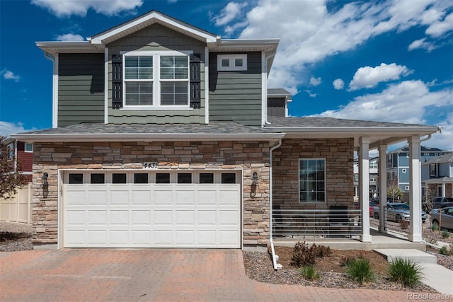 view of front facade with stone siding, a garage, decorative driveway, and roof with shingles