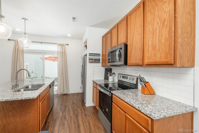 kitchen featuring stainless steel appliances, a sink, dark wood-style flooring, tasteful backsplash, and light stone counters