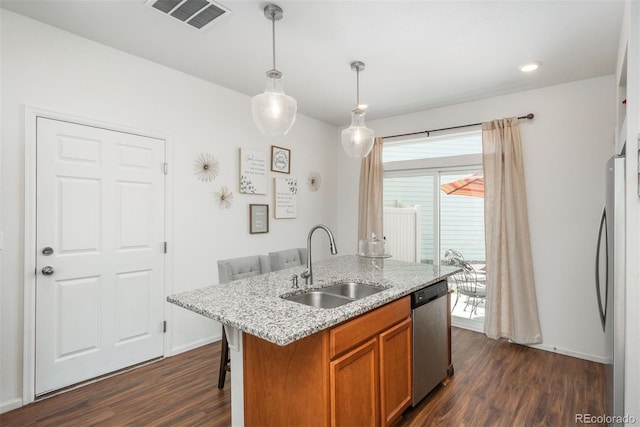 kitchen featuring appliances with stainless steel finishes, a sink, dark wood-type flooring, brown cabinets, and pendant lighting