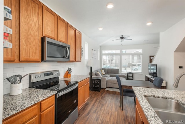 kitchen with stainless steel appliances, a sink, ceiling fan, dark wood-style flooring, and backsplash