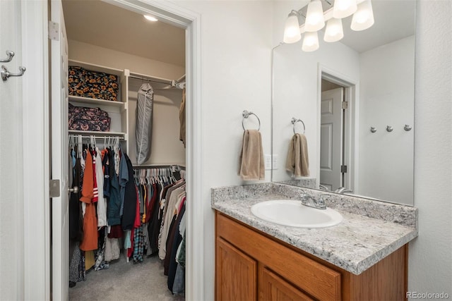 bathroom with a walk in closet and vanity