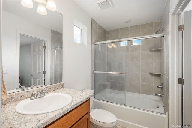 bathroom featuring plenty of natural light, bath / shower combo with glass door, toilet, and vanity