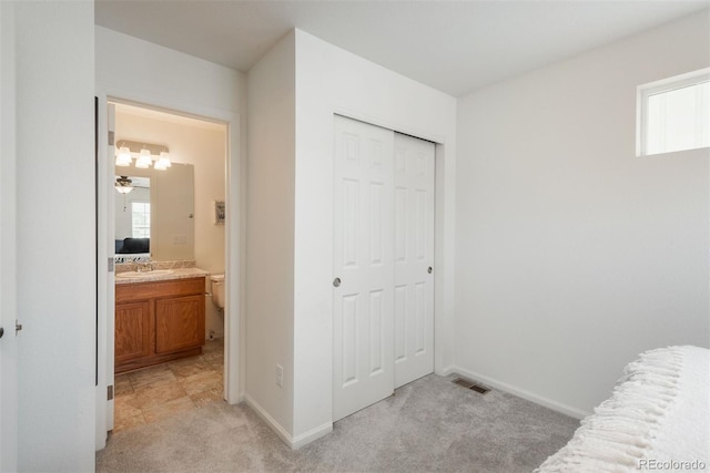 bedroom with light colored carpet, a sink, a closet, and baseboards