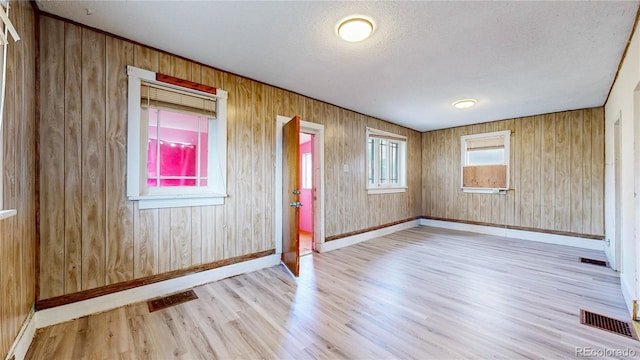 598 S Navajo St, Denver, CO 80223 - unfurnished room with wood finished floors, a textured ceiling, and wood walls