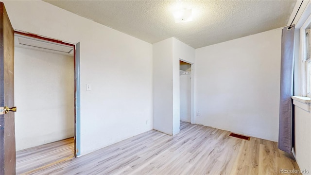 598 S Navajo St, Denver, CO 80223 - unfurnished bedroom featuring wood finished floors, an AC wall unit, a textured ceiling, and a closet