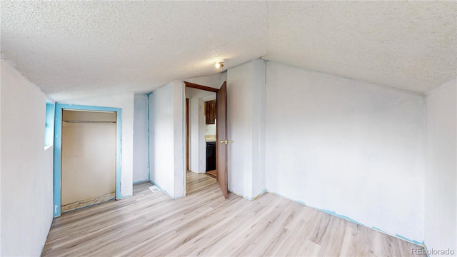598 S Navajo St, Denver, CO 80223 - unfurnished bedroom featuring a textured ceiling, light wood-style flooring, lofted ceiling, and a closet