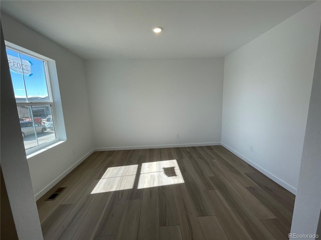 spare room featuring baseboards, visible vents, and wood finished floors