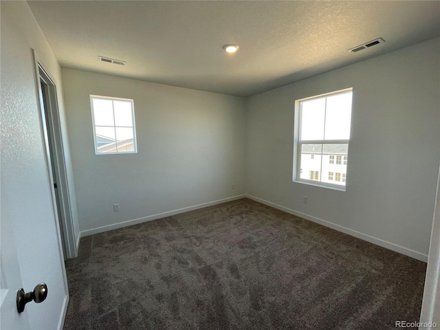 carpeted spare room featuring visible vents, plenty of natural light, and baseboards