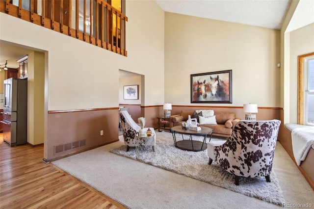 living room with light hardwood / wood-style floors and a high ceiling