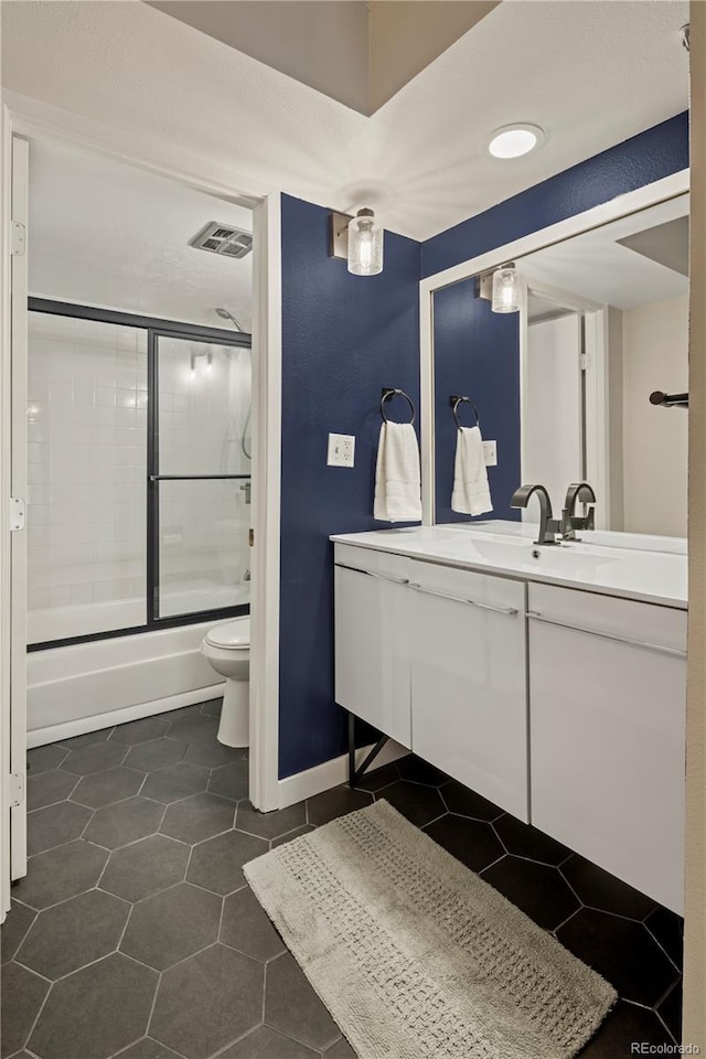 full bathroom with bath / shower combo with glass door, vanity, tile patterned floors, and toilet