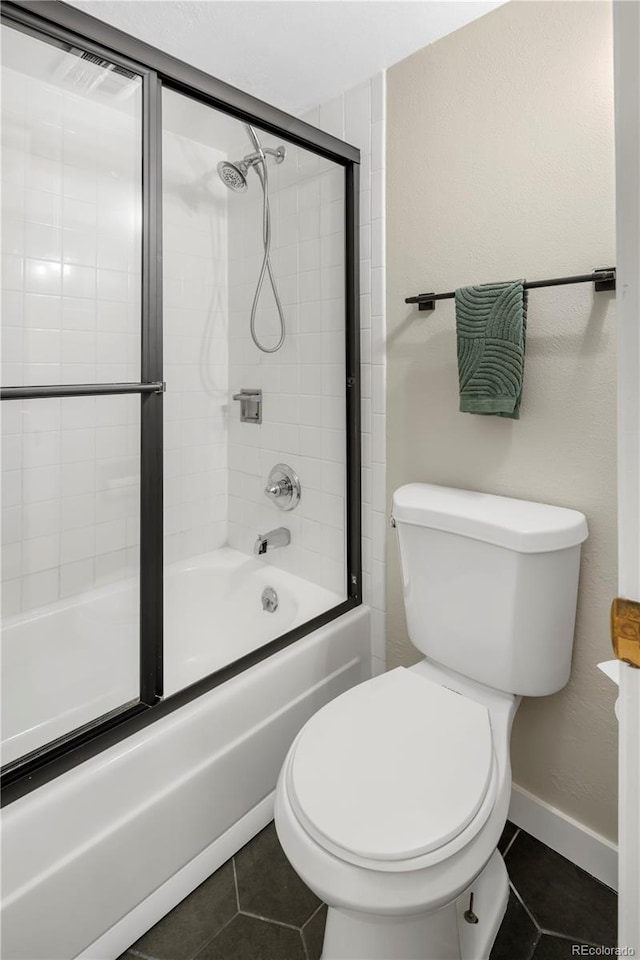 bathroom featuring bath / shower combo with glass door, tile patterned floors, and toilet