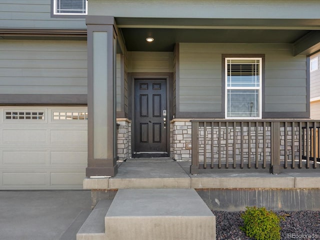 8850 Sedalia St, Commerce City, CO 80022 - view of exterior entry with covered porch, a garage, and stone siding